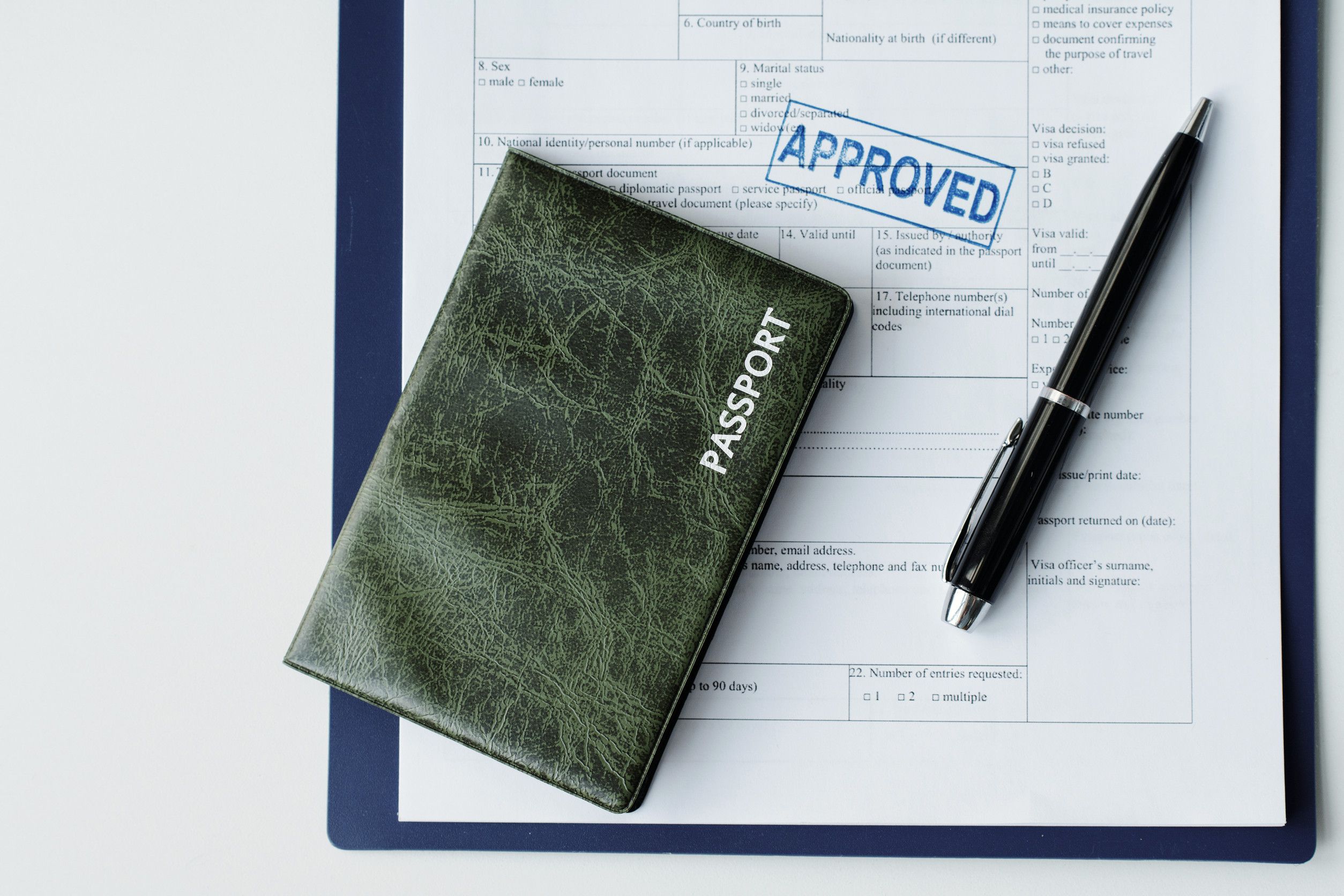 Top down flat lay of passport in dark green leather cover travel visa application paper with