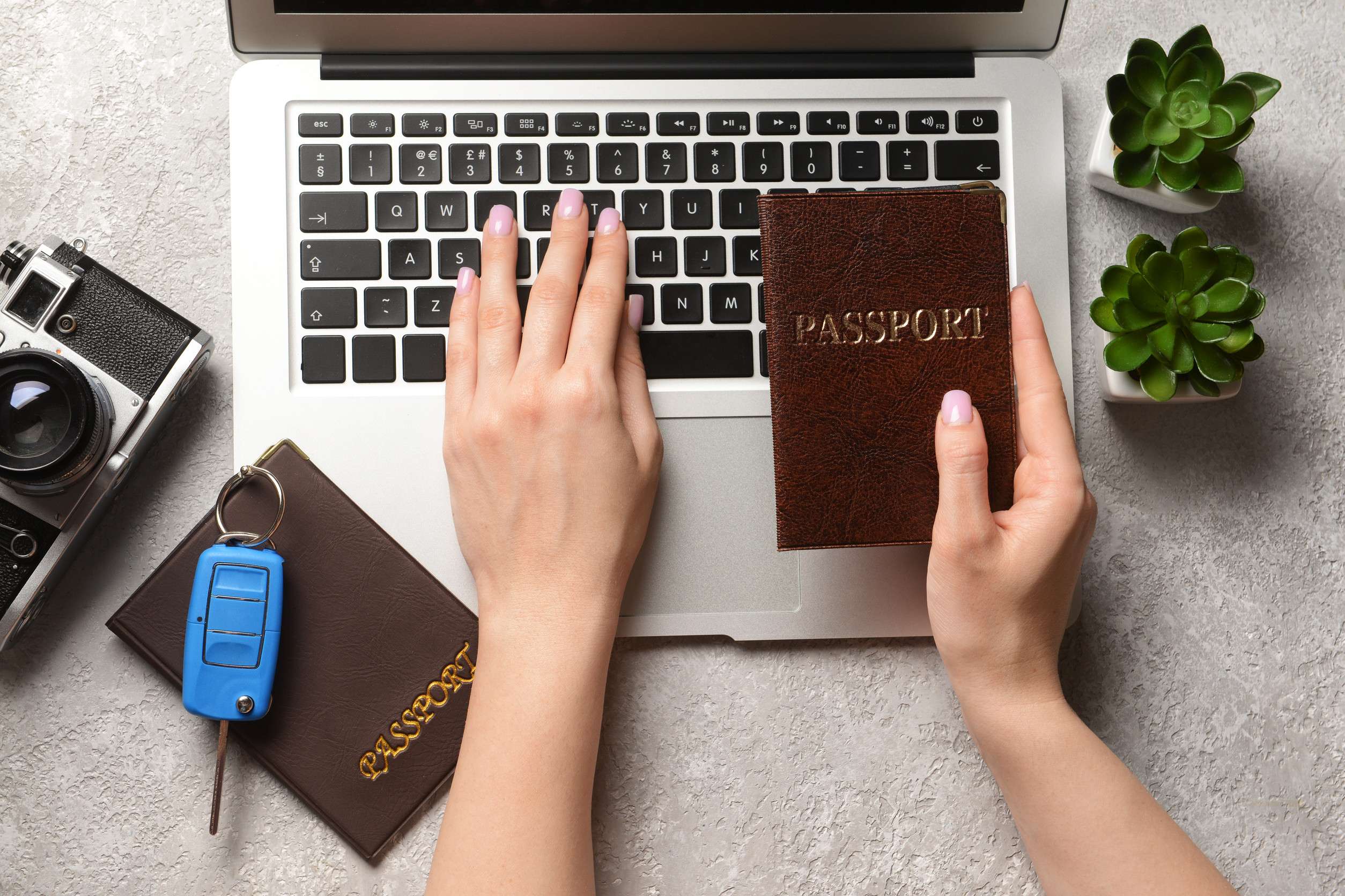 Typing on laptop holding passport